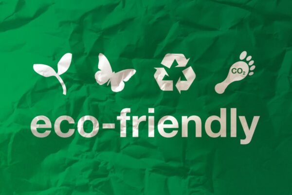 A imagem possui o fundo verde com uma textura de papel amassado, com os ícones em formato de planta, borboleta, símbolo da reciclagem e pegada ambiental, com o dizer "eco-friendly" abaixo, em tradução livre: "amigável ao planeta", referindo-se ao marketing verde.